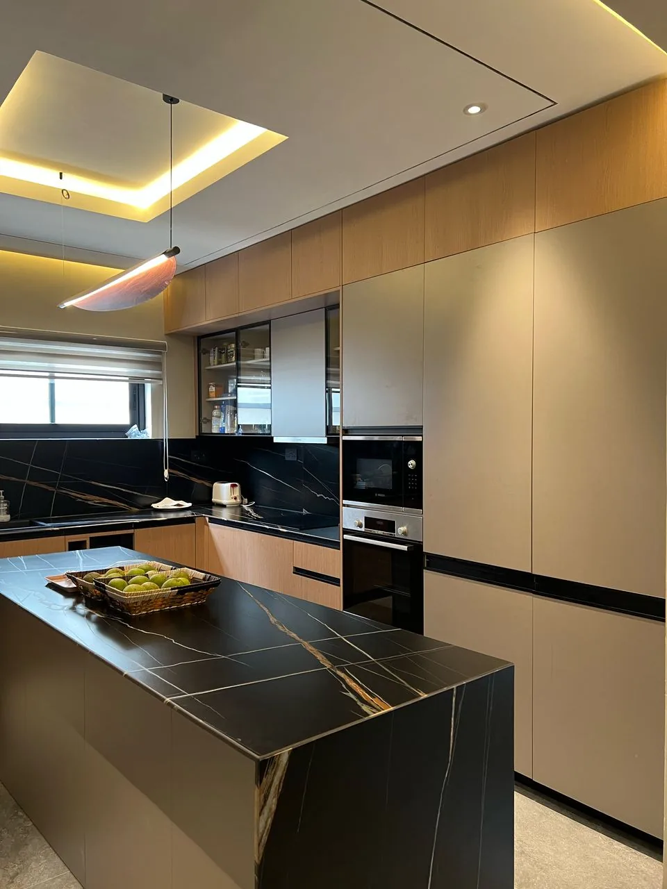 Fitted kitchen with a black stone island and tall cabinetry, an Enzo Living project